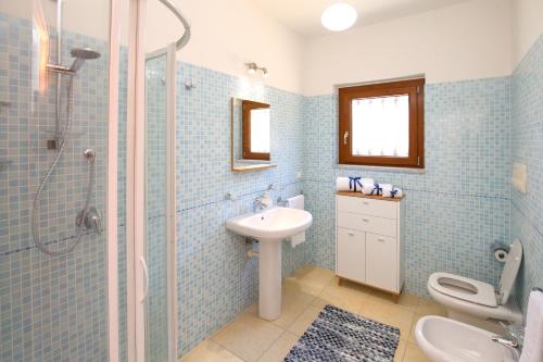 y baño de azulejos azules con lavabo y ducha. en Swimming Pool and Relax Apartment, en Castelsardo