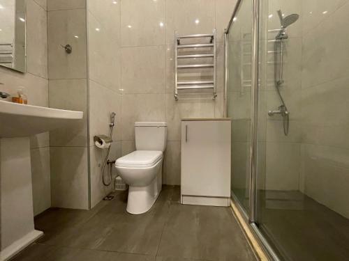 a bathroom with a toilet and a glass shower at Azure apart in Baku