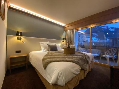 a hotel room with a large bed with a balcony at Hôtel Macchi Restaurant & Spa in Châtel