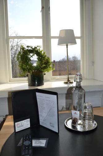 a table with a laptop computer and a bottle on it at Lilla Hotellet Bed & Breakfast i Alingsås in Alingsås