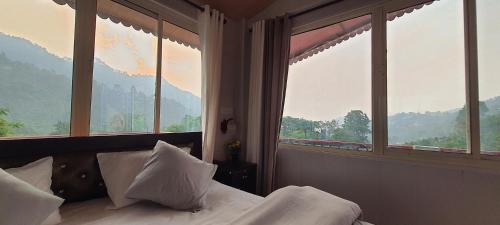 a bedroom with a bed with views of mountains at Karthik Resorts, Jeolikote Nainital in Nainital