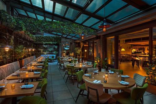 a restaurant with wooden tables and chairs and plants at Moxy NYC East Village in New York