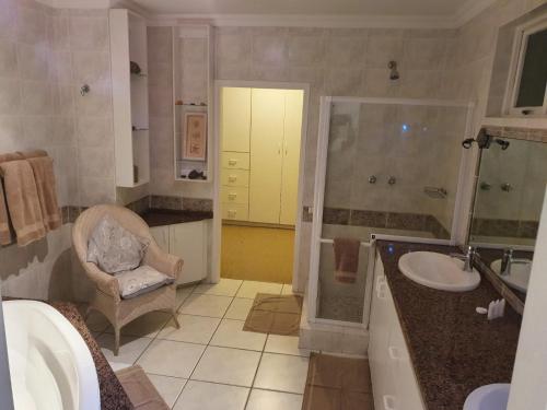 a bathroom with a sink and a shower and a chair at Ingwe Manor Guesthouse in Margate