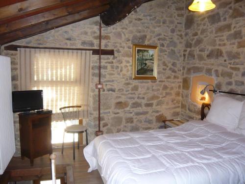 a bedroom with a bed and a stone wall at Agriturismo Petrarosa in Neviano degli Arduini