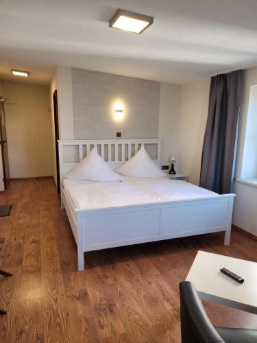 a large white bed in a room with a table at Pension Am Ozeaneum in Stralsund