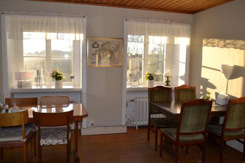 a dining room with a table and chairs and windows at Lilla Hotellet Bed & Breakfast i Alingsås in Alingsås