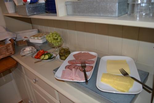 a kitchen counter with meat and cheese and vegetables at Lilla Hotellet Bed & Breakfast i Alingsås in Alingsås