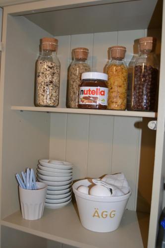 a pantry with jars and dishes on a shelf at Lilla Hotellet Bed & Breakfast i Alingsås in Alingsås
