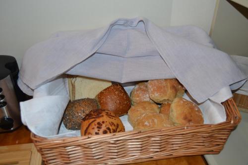 a basket filled with lots of different types of bread at Lilla Hotellet Bed & Breakfast i Alingsås in Alingsås