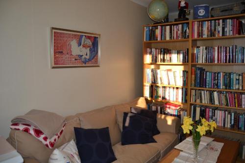 a living room with a couch and book shelves filled with books at Lilla Hotellet Bed & Breakfast i Alingsås in Alingsås