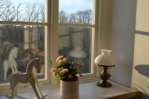 a window with a horse statue and a vase of flowers at Lilla Hotellet Bed & Breakfast i Alingsås in Alingsås