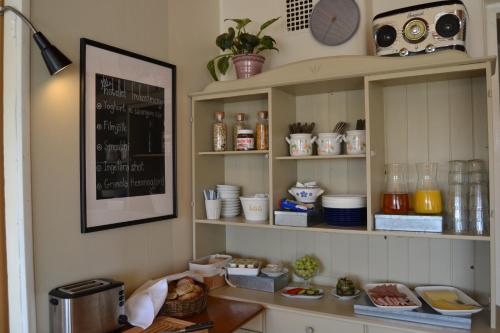 a kitchen with shelves with dishes and a clock on the wall at Lilla Hotellet Bed & Breakfast i Alingsås in Alingsås