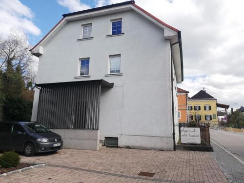 una casa blanca con un coche aparcado delante de ella en Alte Innbrücke, en Schärding