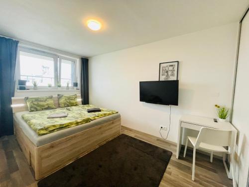 a bedroom with a bed and a desk and a television at New apt in new building located begin of Petrzalka in Bratislava