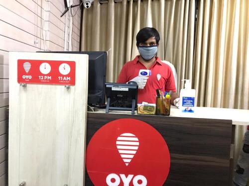 un hombre con una máscara en un escritorio con una computadora en OYO Chaithanya Complex en Muttam