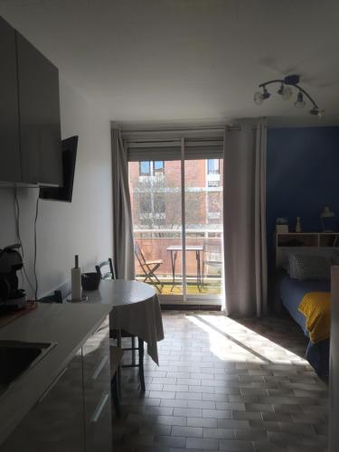 Il comprend une cuisine avec une table et une fenêtre avec une terrasse. dans l'établissement Jolie studio 2 étoiles proche de l'étang de thau, à Balaruc-les-Bains