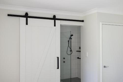 a bathroom with white walls and a shower stall at Djilba Cottage at Windance in Yallingup