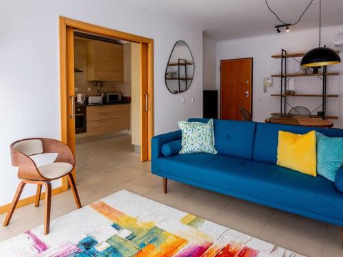 a living room with a blue couch and a kitchen at Central Caldas w/ AC & Fast Net in Caldas da Rainha