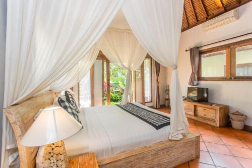 een slaapkamer met een hemelbed en een televisie bij Ubud Luwih Nature Retreat in Ubud