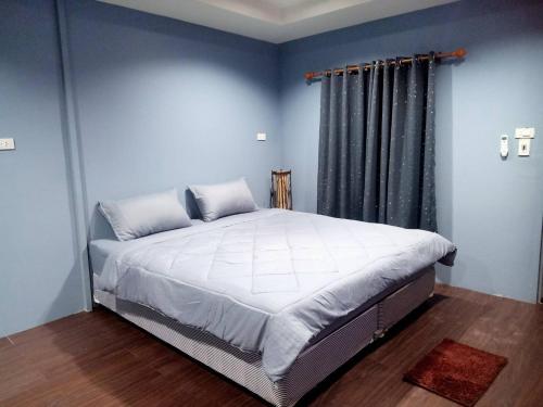 1 dormitorio con 1 cama grande y paredes azules en เฮือนพรนาคา โฮมสเตย์, en Ban Don Klang