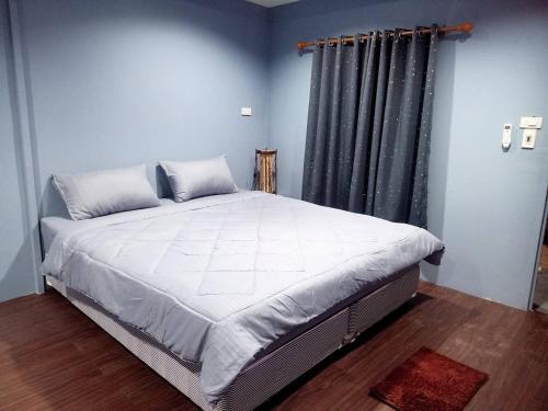 a large bed in a bedroom with a window at เฮือนพรนาคา โฮมสเตย์ in Ban Don Klang