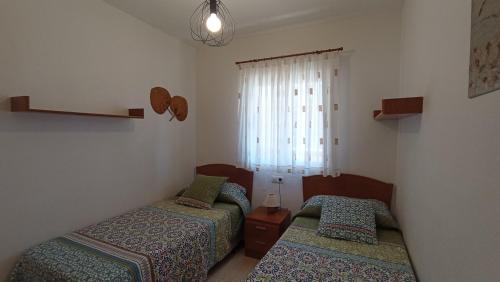 twee bedden in een kleine kamer met een raam bij Bonito apartamento en Marina D'or [1ra línea de playa] in Oropesa del Mar