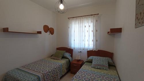 dwa łóżka w małym pokoju z oknem w obiekcie Bonito apartamento en Marina D'or [1ra línea de playa] w mieście Oropesa del Mar