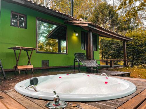 uma banheira no deque de uma casa verde em Pousada Espelho Dagua em Gonçalves