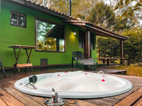 a bath tub on the deck of a green house at Pousada Espelho Dagua in Gonçalves