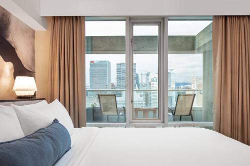 een hotelkamer met een bed en een groot raam bij Delta Hotels by Marriott Vancouver Downtown Suites in Vancouver