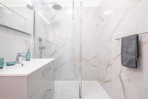 a white bathroom with a shower and a sink at Villa Ana D'Arfet in Água de Pena