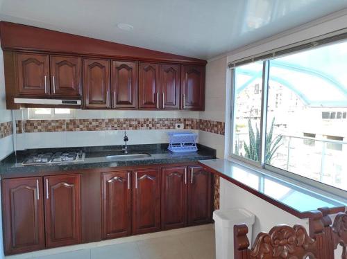 una cocina con armarios de madera y una gran ventana en Apartamento en el Corazón de Paipa., en Paipa
