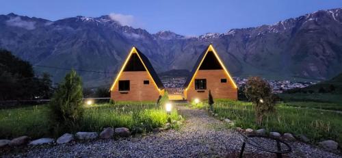 una casa en un campo con montañas en el fondo en Little Wood House Gergeti, en Kazbegi