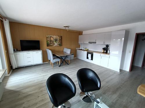 ein Wohnzimmer mit einem Tisch und Stühlen sowie eine Küche in der Unterkunft Landhaus Dahlem in Hahnenklee-Bockswiese