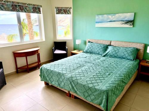 1 dormitorio con 1 cama con edredón verde en Blue Emerald Beachfront Blessing en Willemstad