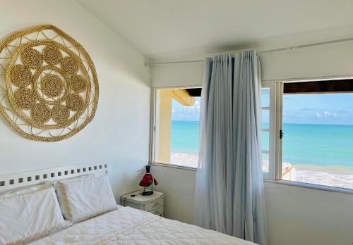 a bedroom with a bed and a window with the ocean at Paraíso na areia da praia in Maceió