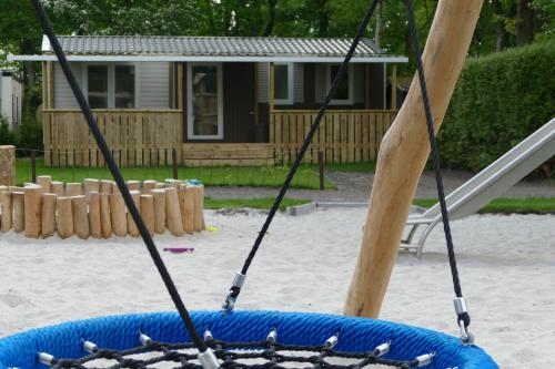 a swing in a playground with a house in the background at VerandaChalet 6p centrally located in National Park, Swimming pool 164 in Wateren