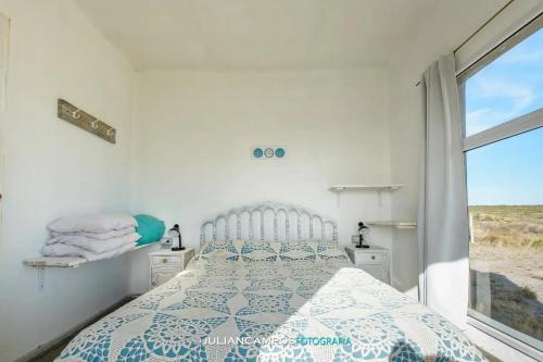 a white bedroom with a bed and a window at Casa de Mar El Qubito las Grutas in Las Grutas