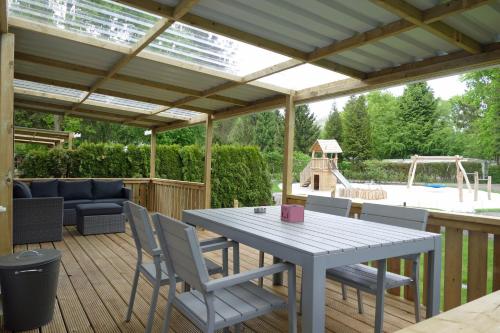 un patio con mesa y sillas en una terraza en VerandaChalet 6p centrally located in National Park, Swimming pool, en Wateren