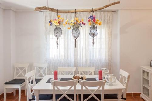 a white dining room with a white table and chairs at Chalet junto a playa de Suances in Suances