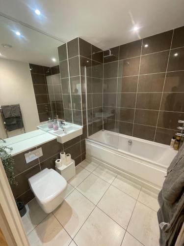 a bathroom with a toilet and a tub and a sink at Luxury London Apartment - Steps To East Croydon Train Station in Croydon