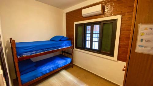 a room with two bunk beds and a window at Casa uma Quadra da Praia das Asturias com área gourmet in Guarujá