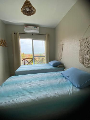 two beds sitting in a room with a window at Lindo Flat Na Paradisíaca Praia da Taíba in Taíba