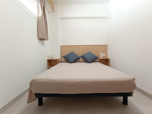 a bed with two blue pillows in a white room at Apartamento en El Prado in Cullera