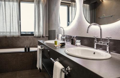 a bathroom with two sinks and a large mirror at Valsana Hotel Arosa in Arosa