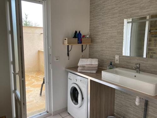 uma casa de banho com uma máquina de lavar roupa e um lavatório em Gîte La Maison de JuJu em Lacave