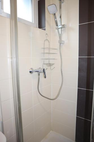 a shower with a shower head in a bathroom at Le Dugois centre-ville Belfort in Belfort