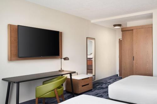 a hotel room with a desk and a tv on the wall at Fairfield Inn & Suites Tampa Riverview in Riverview