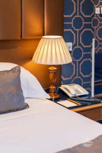 a lamp on a desk with a bed and a phone at Burlington House Boutique in Oxford