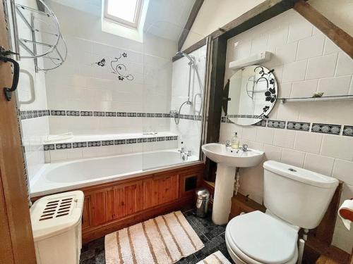 a bathroom with a tub and a toilet and a sink at STONE BUILT BARN in a beautiful RURAL setting in Llangwm-isaf